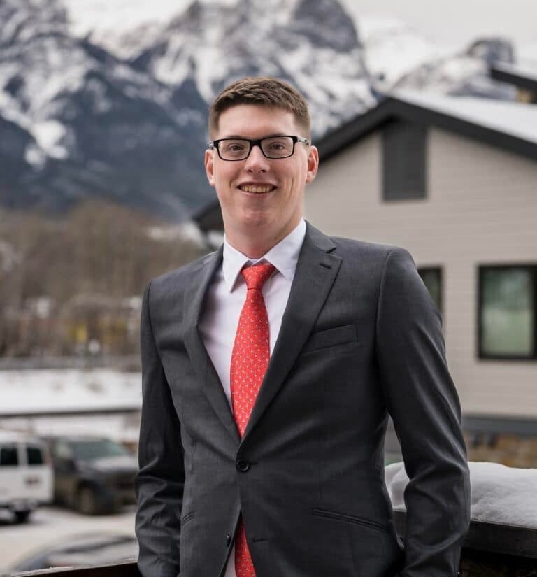 Drake Miller, founder of Mailr, in a suit in front of the Rocky Mountains