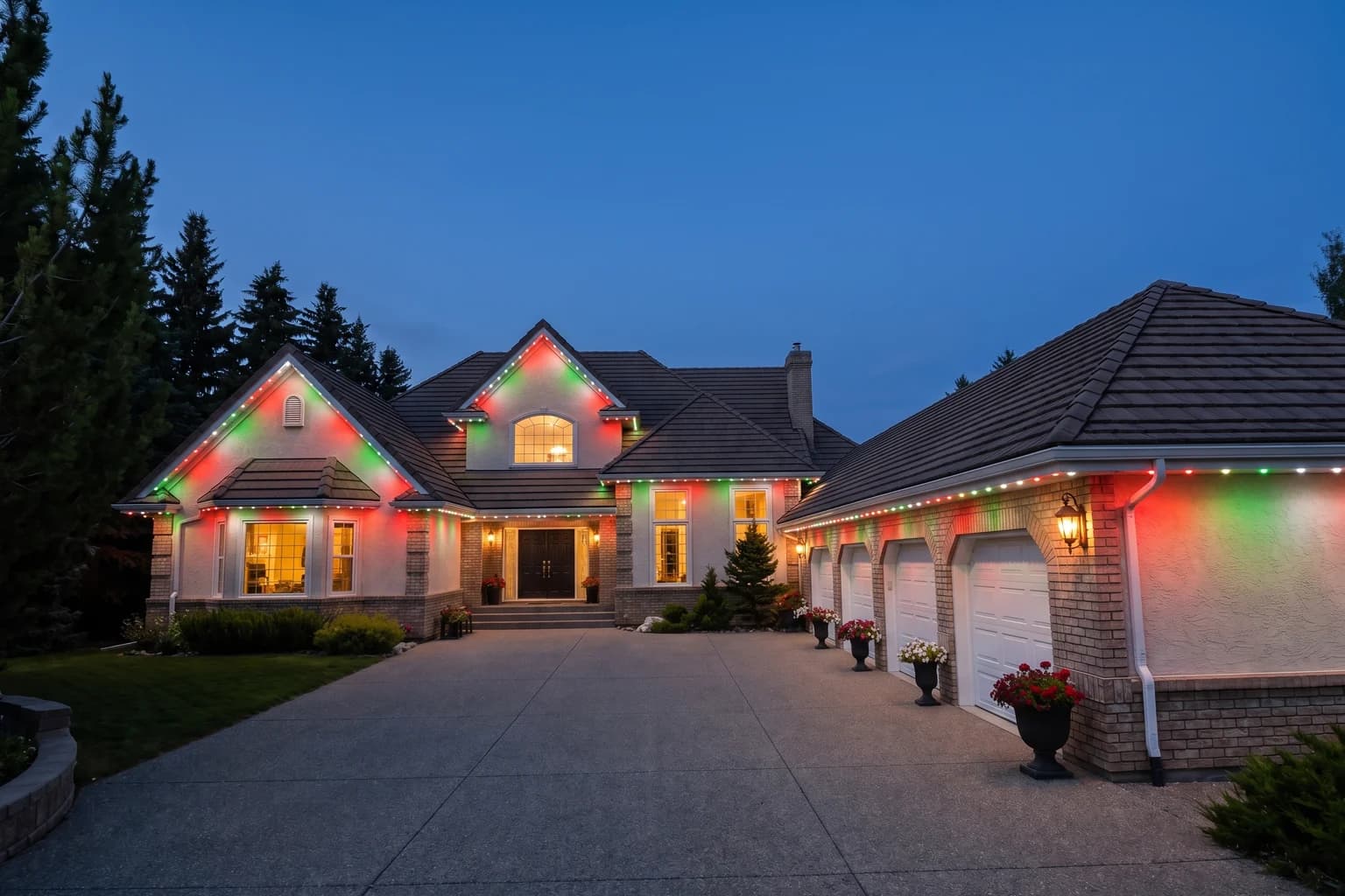 The same home at dusk with red, white, and green runs along every roofline